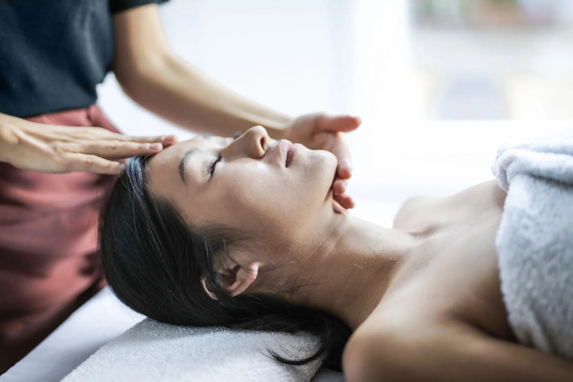 A client resting with eyes closed during a head and face massage.
